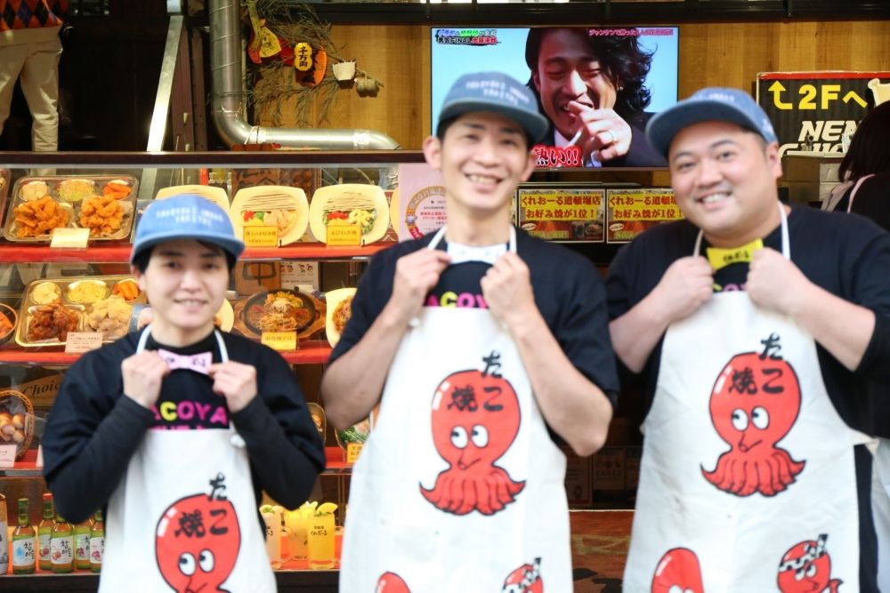 Fazendo takoyaki e tacos em Dotonbori. Por favor, forneça um atendimento ao cliente que faça os turistas estrangeiros sorrirem.