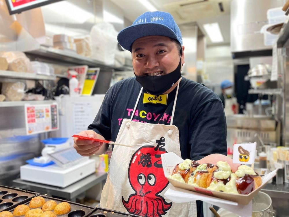 Fazendo takoyaki e tacos em Dotonbori. Por favor, forneça um atendimento ao cliente que faça os turistas estrangeiros sorrirem.